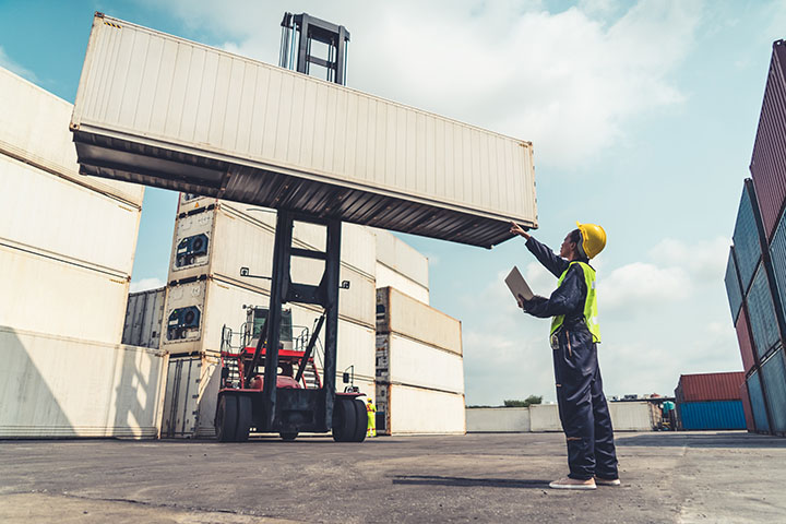 Image: Dock worker handling shipper container in yard.