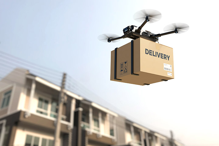 Image: Drone flying in the sky with package that says 'delivery'.