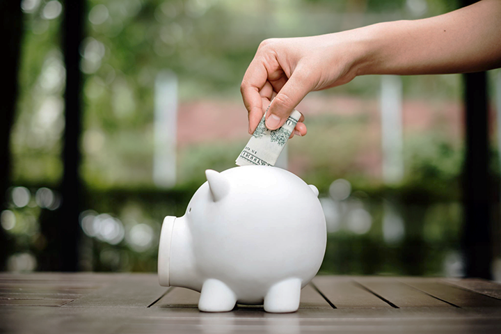Image: An ecommerce seller inserting savings into a piggy bank.