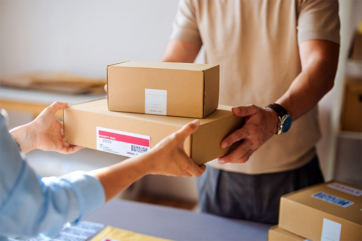 Image: Two warehouse workers carrying a package in a shipment warehouse.