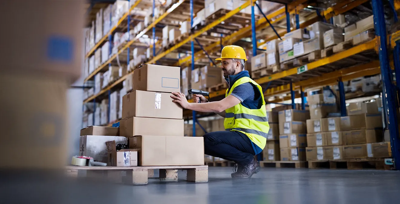 Image: A warehouse worker looking over packages at a third-party logistics center.