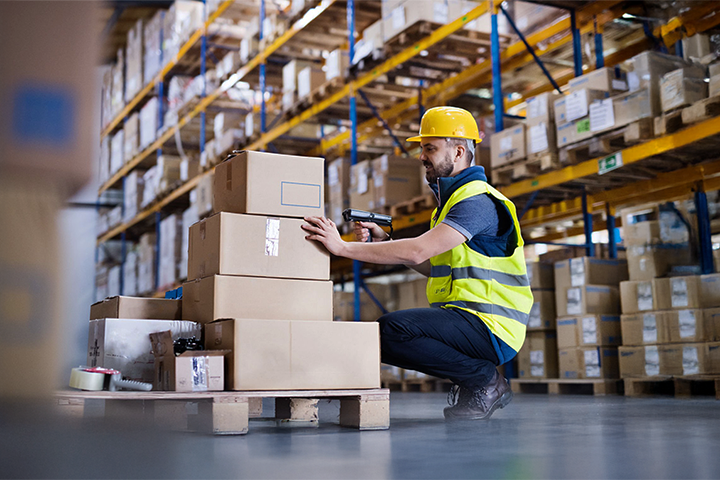 Image: A warehouse worker looking over packages at a third-party logistics center.
