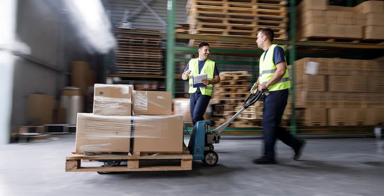 Image: Two warehouse workers moving a pallet of consolidated shipments.