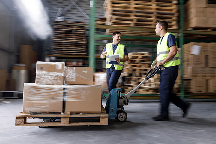 Image: Two warehouse workers moving a pallet of consolidated shipments.