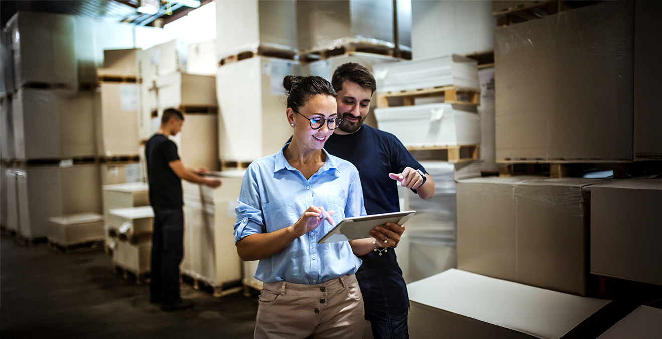 Image: Two workers using a warehouse management system to manage packages.