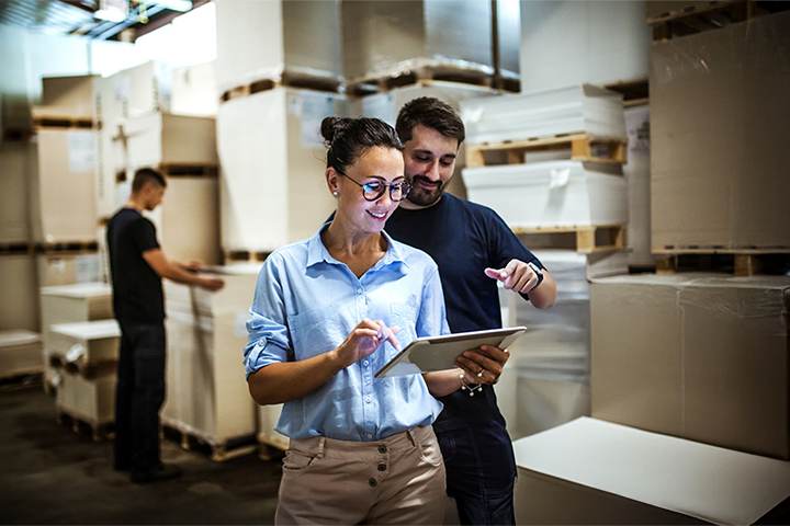 Image: Two workers using a warehouse management system to manage packages.