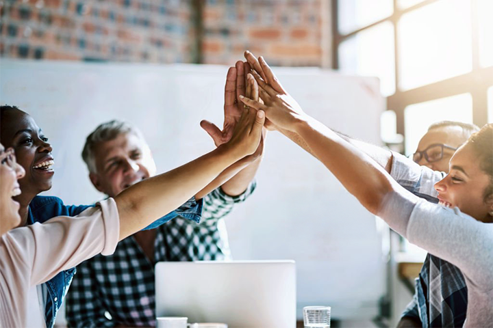Image: A happy tech team giving a group high five.